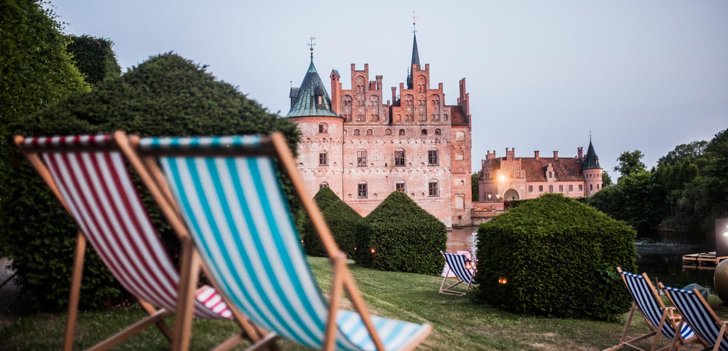 To af de klassiske stribede strand-liggestole i forgrunden - Egeskov Slot i baggrunden.