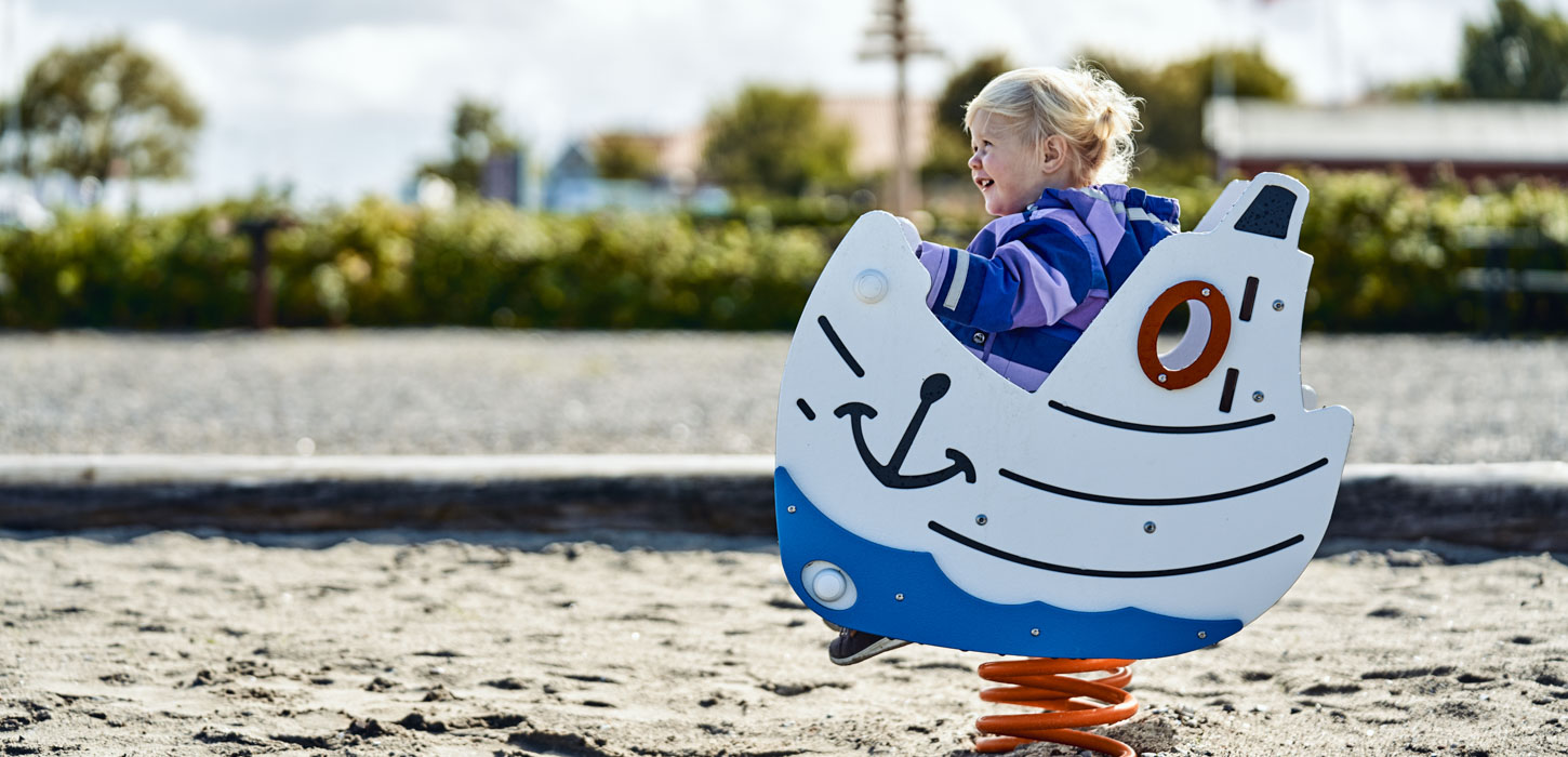 Barn leger på fjeder-legeredskab i sandkasse på legeplads