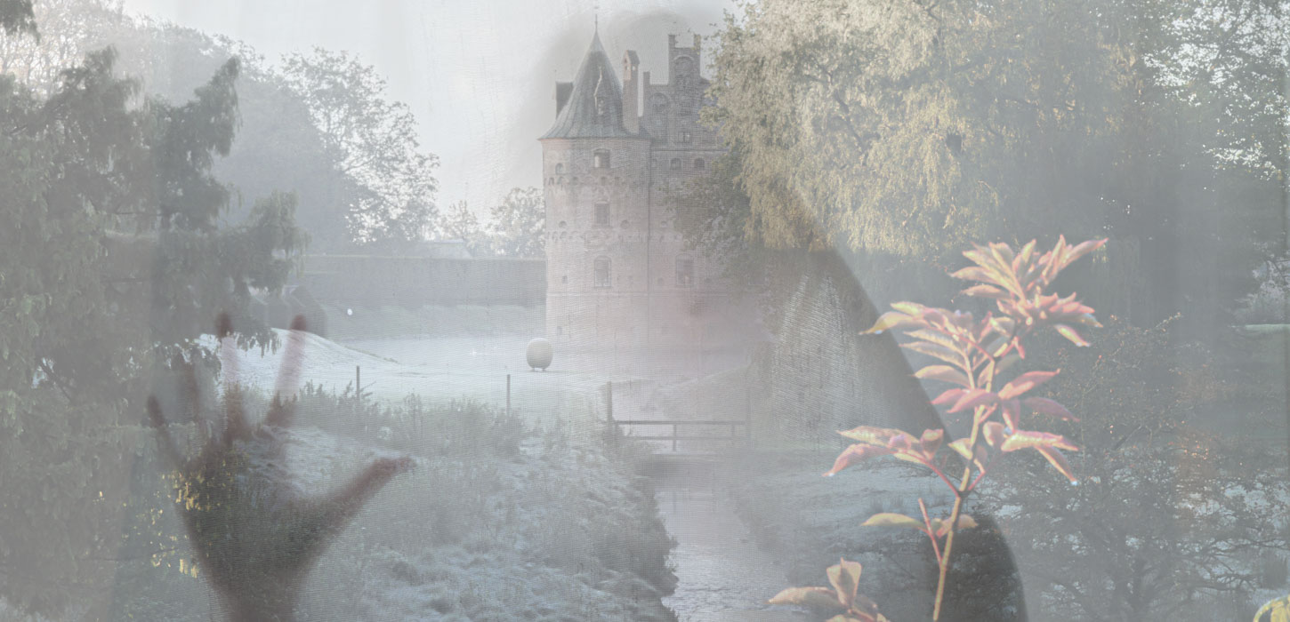 Egeskov Slot set fra afstand gennem en tåge med omridset af et spøgelse.