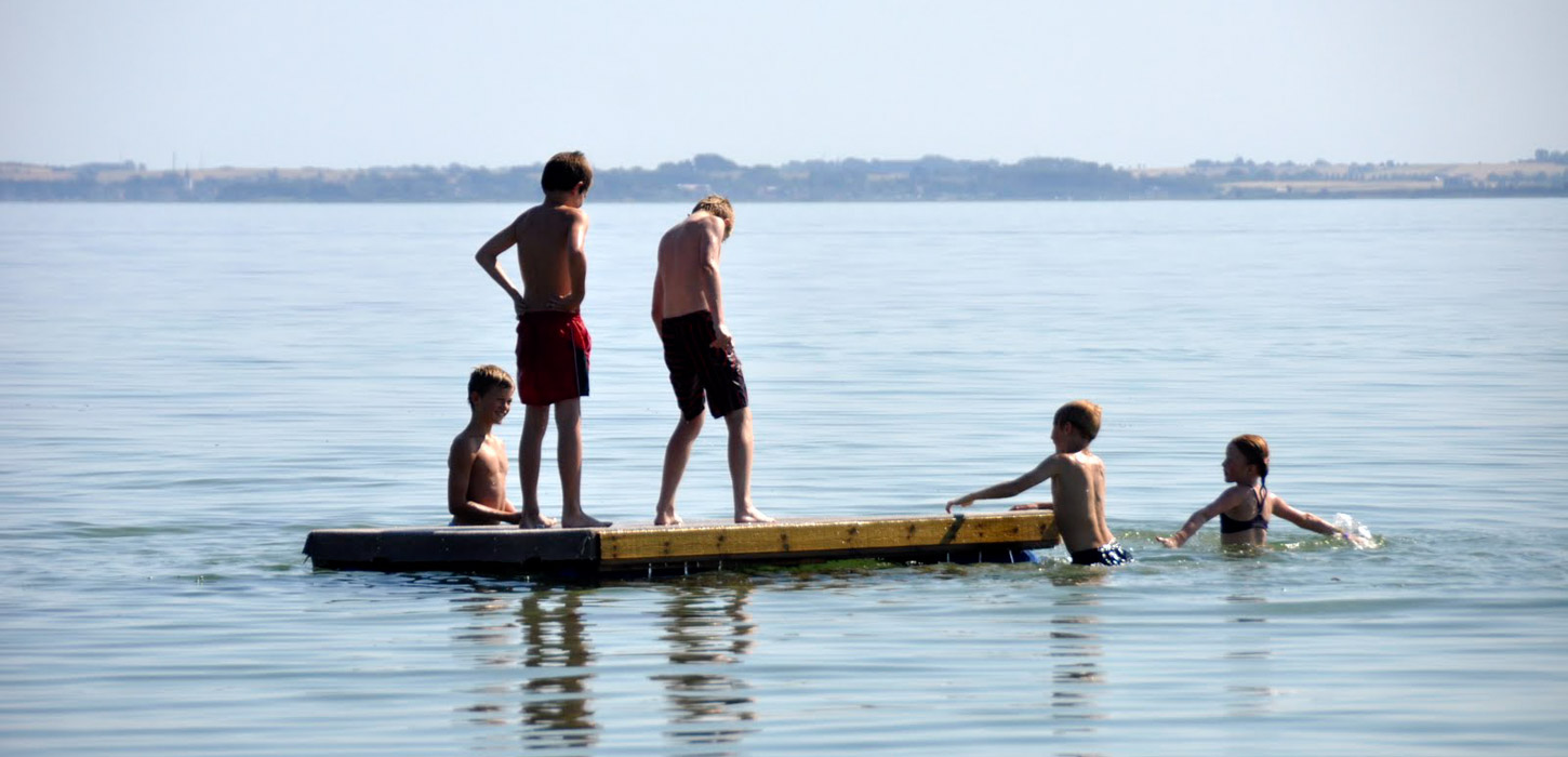 5 børn er på og omkring en floatee i vandet.