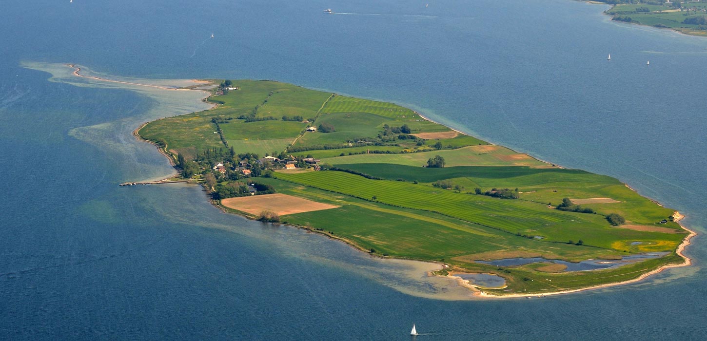 Bjørnø set fra luften, omkranset af vand til alle sider.
