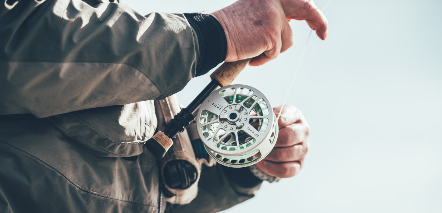 Nærbillede af fiskehjul på fiskestang, som en fisker står og fisker med.