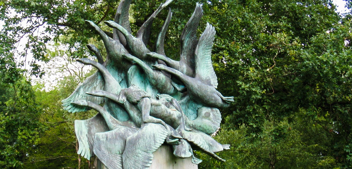 Foran et træ står en skulptur af svaner og en kvinde