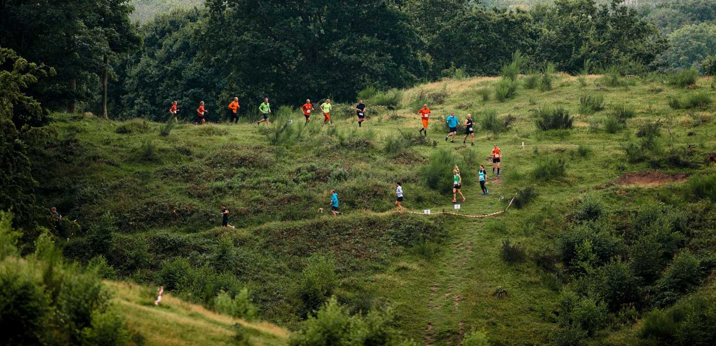En stor gruppe mennesker i forskelligfarvet løbetøj løber i en lang række ved Svanninge Bakker. 