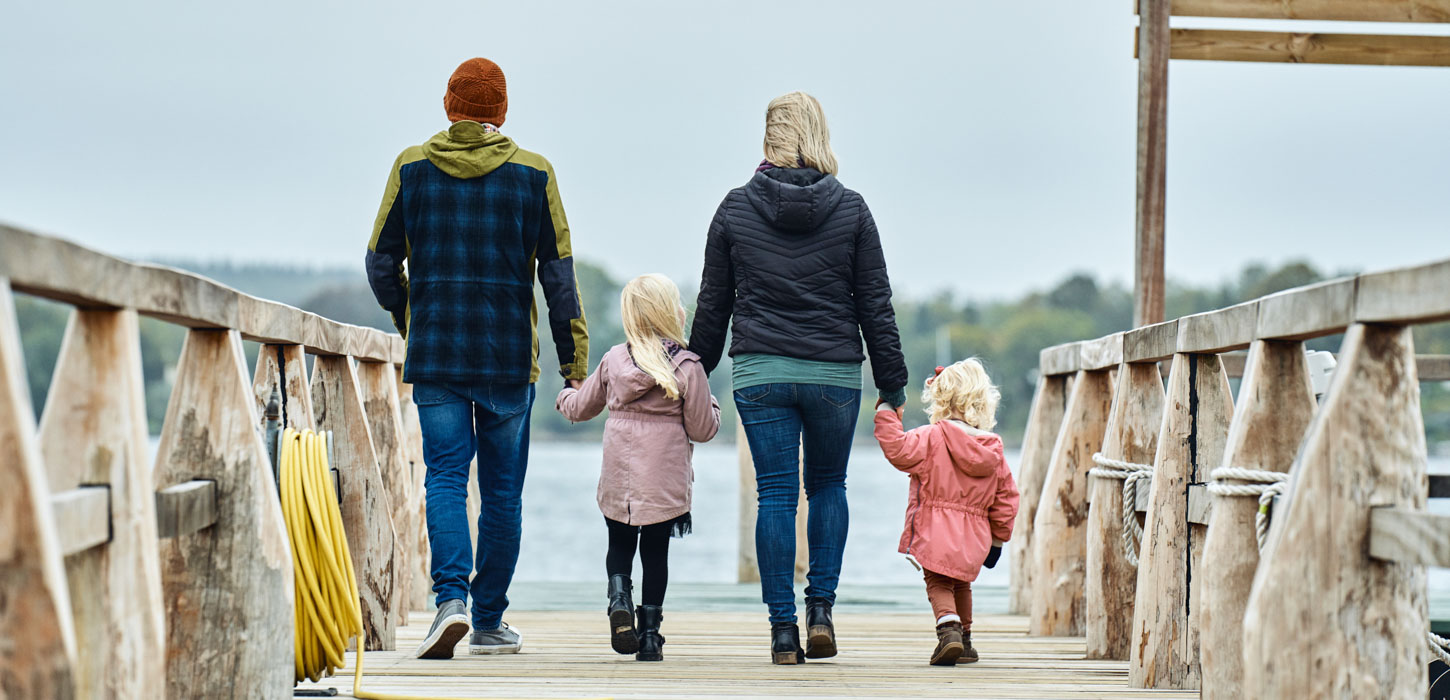 Familie på badebro i Troense på Tåsinge - to voksne og to børn går med ryggen til og holder i hånd