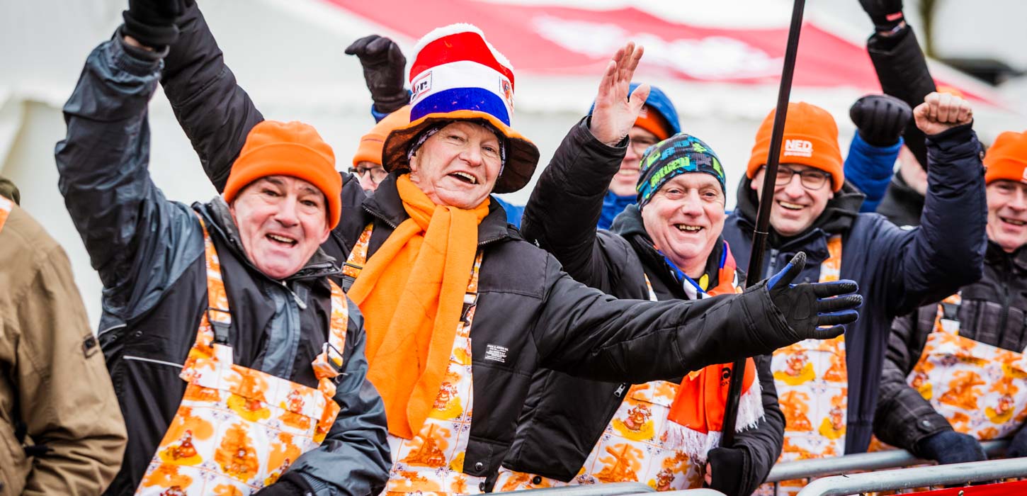 Cyklecrossfans til cykelevent i Bogense på Fyn står påklædte i orange farver og med hatte på.