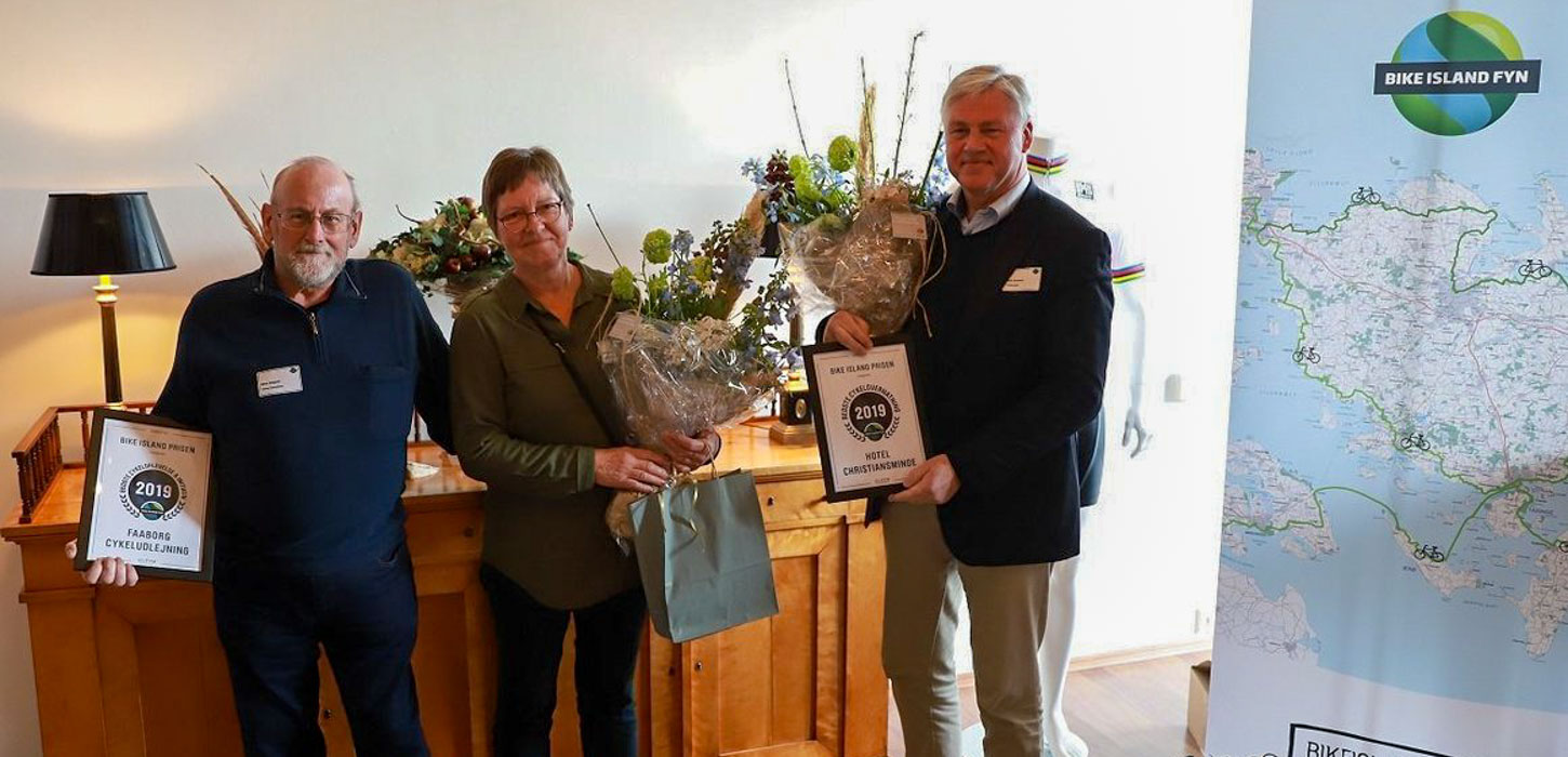 Tre glade modtagere af Bike Island-prisen på Fyn 2019 står med deres overrakte blomster og diplom.