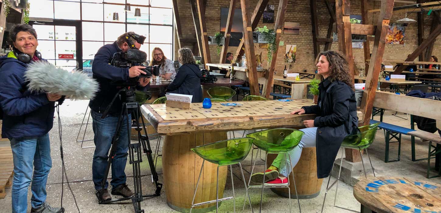 Et lille hold interviewer en person ved et bord på et streetfood-marked.