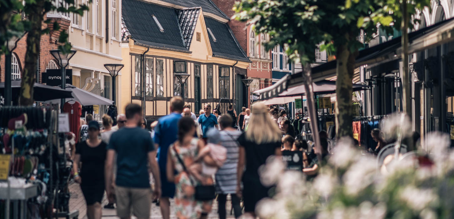 En gågade fyldt med mennesker på en varm dag. 