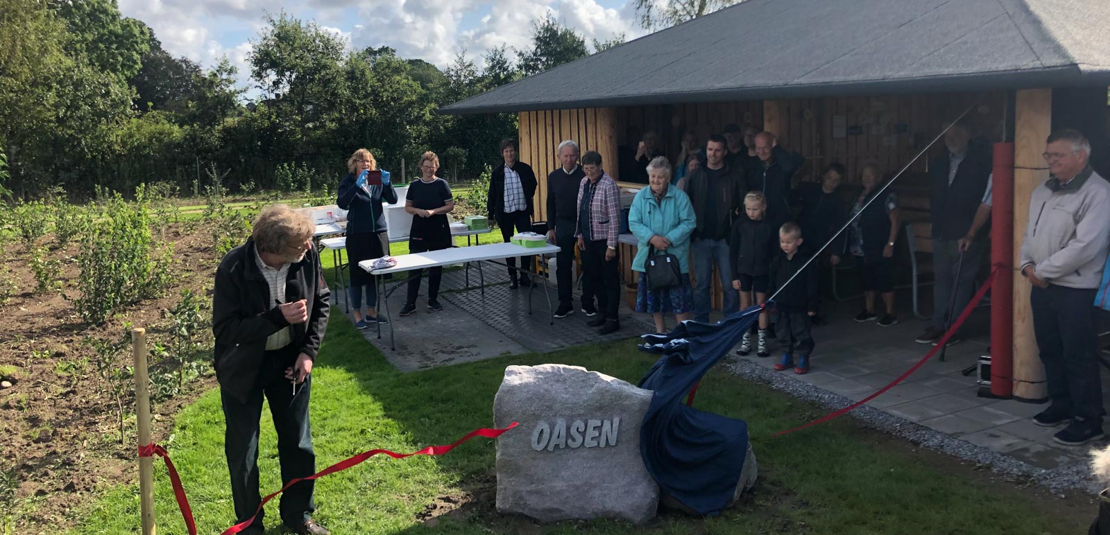 Mand klipper en rød snor over til åbningen af Oasen. Begejstrede folk kigger på i et skønt solskinsvejr. 