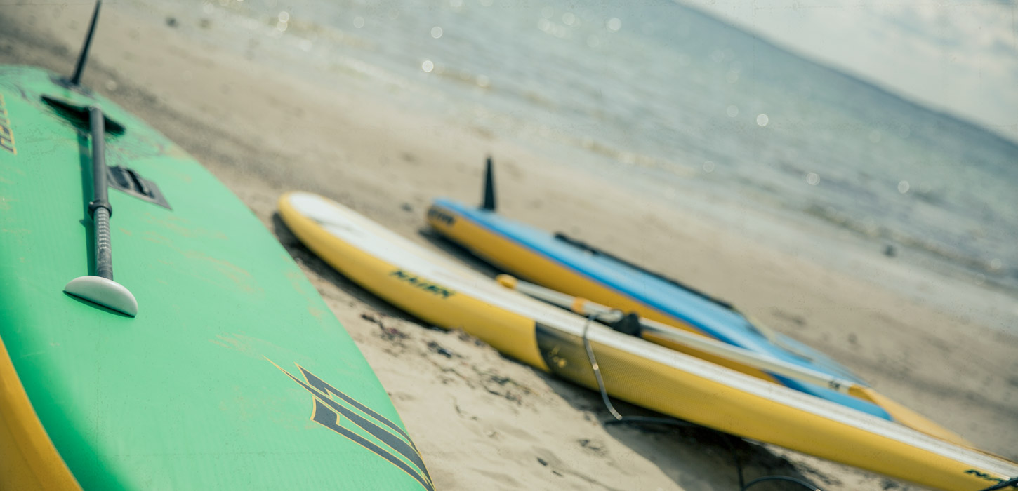 Paddle boards liggende på en strand.