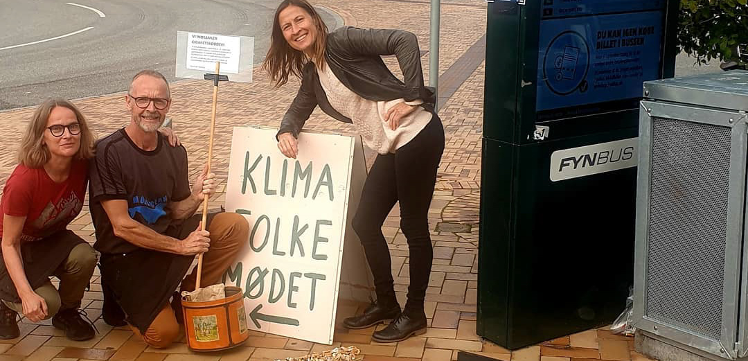 Stationen Kaffebar engagerer sig, hver gang der er store events i Middelfart - her sidder 3 mennesker ved et skilt i forbindelse med Klimafolkemødet.