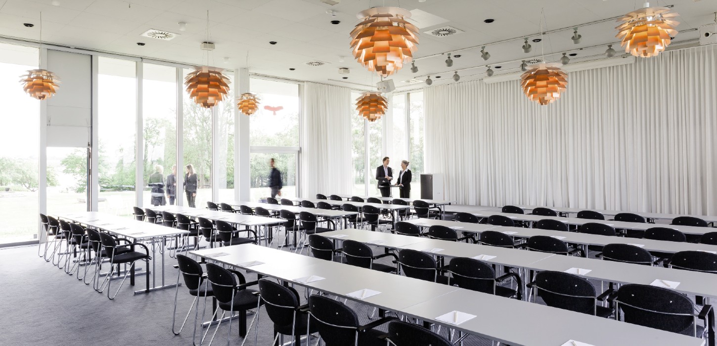 Stort lyst mødelokale med ens, klassiske lamper i loftet.