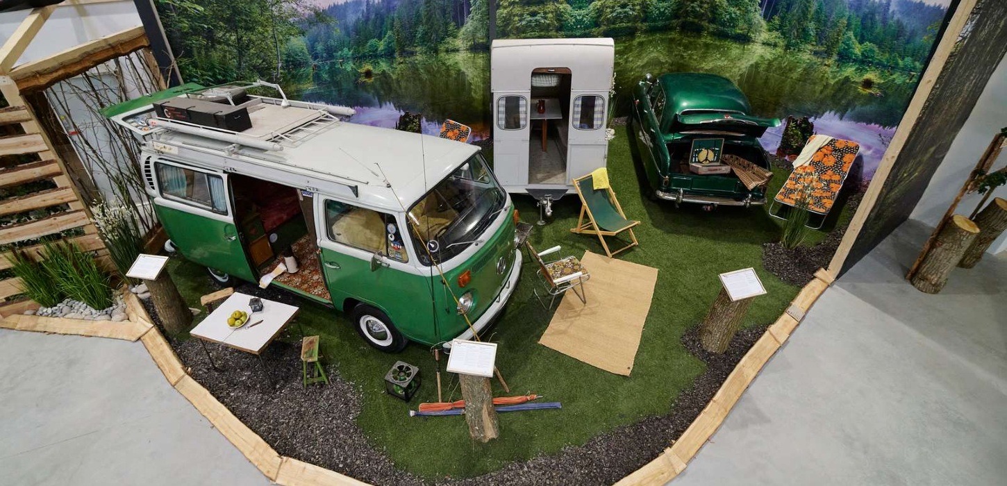 Gammel grøn retro- camping-van fra VolksWagen er udstillet med forskellige tilsvarende retro-campingeffekter rundt om.