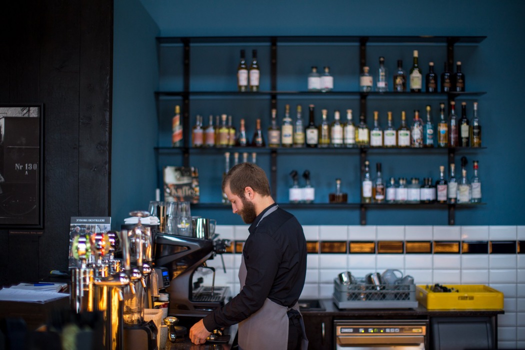 En mandlig barista står bag baren på en restaurant.