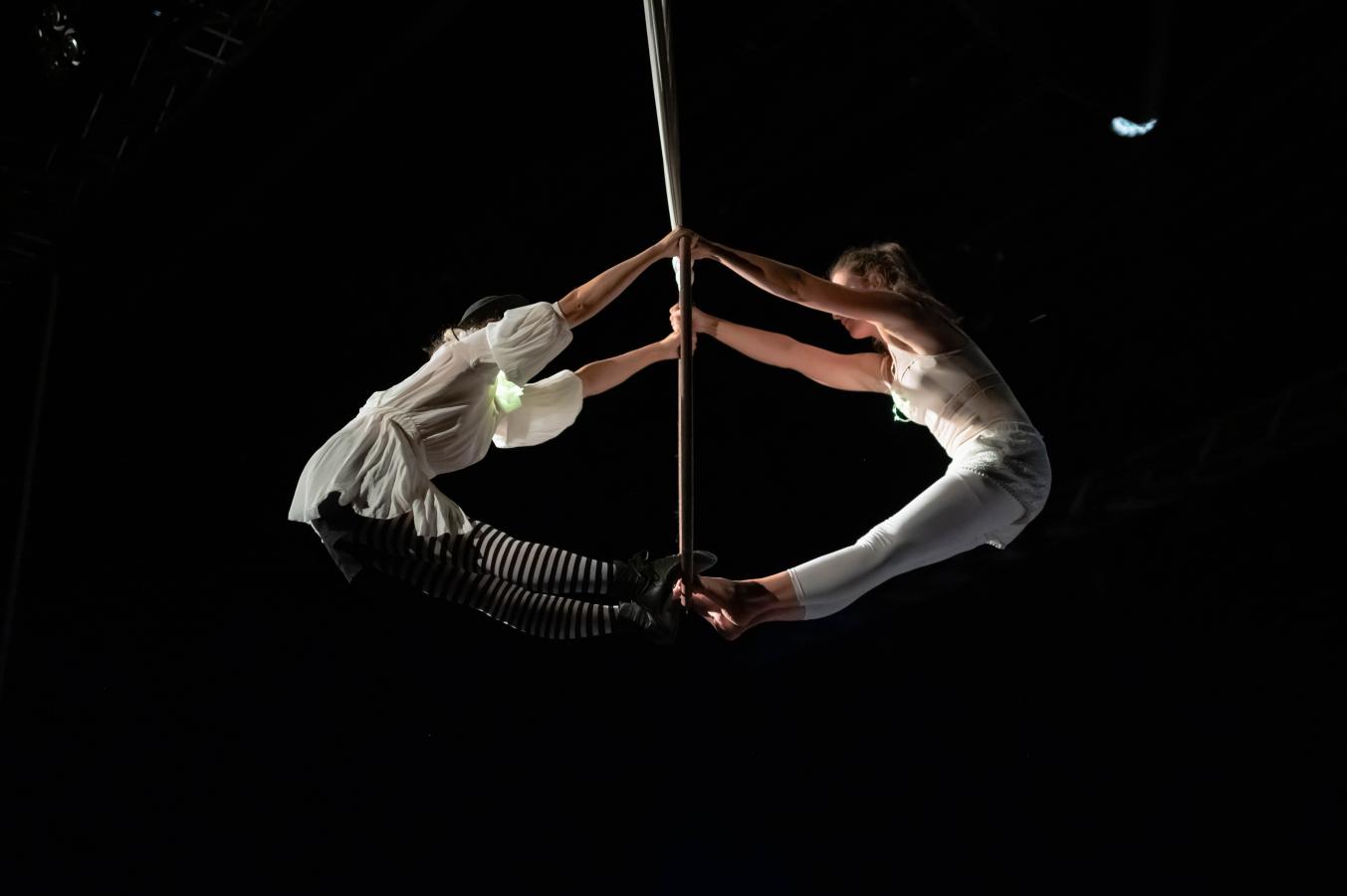 To artister klædt i hvidt svæver sammen i et sort rum.