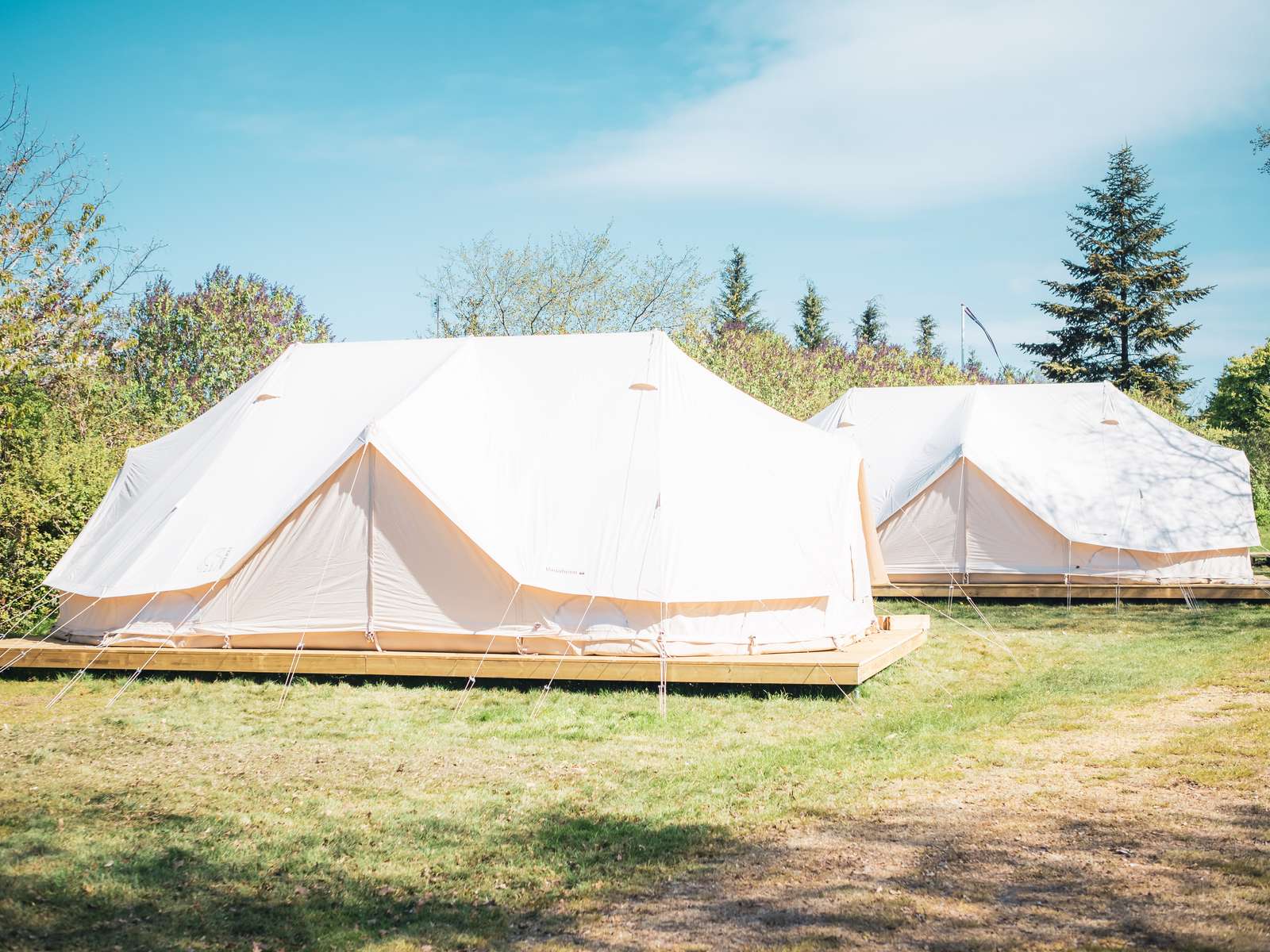 To hvide glampingtelte omringet af natur.