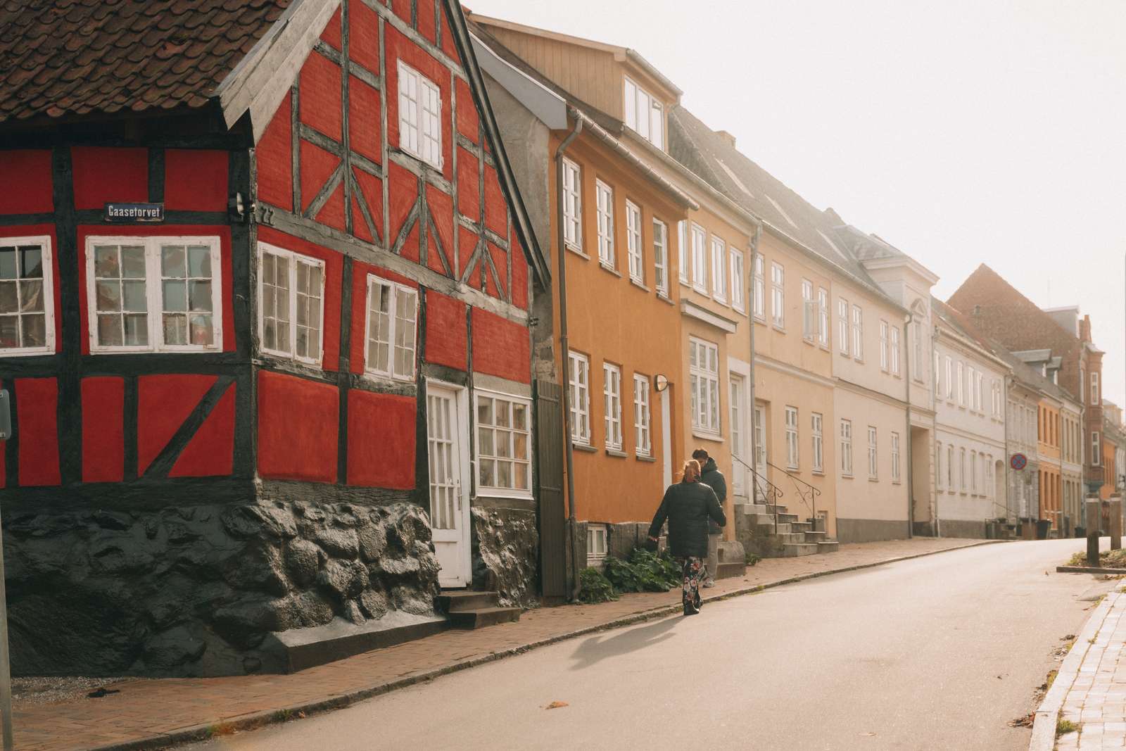 Farverige rækkehuse i gammel stil. En mand går på gaden forbi husene.