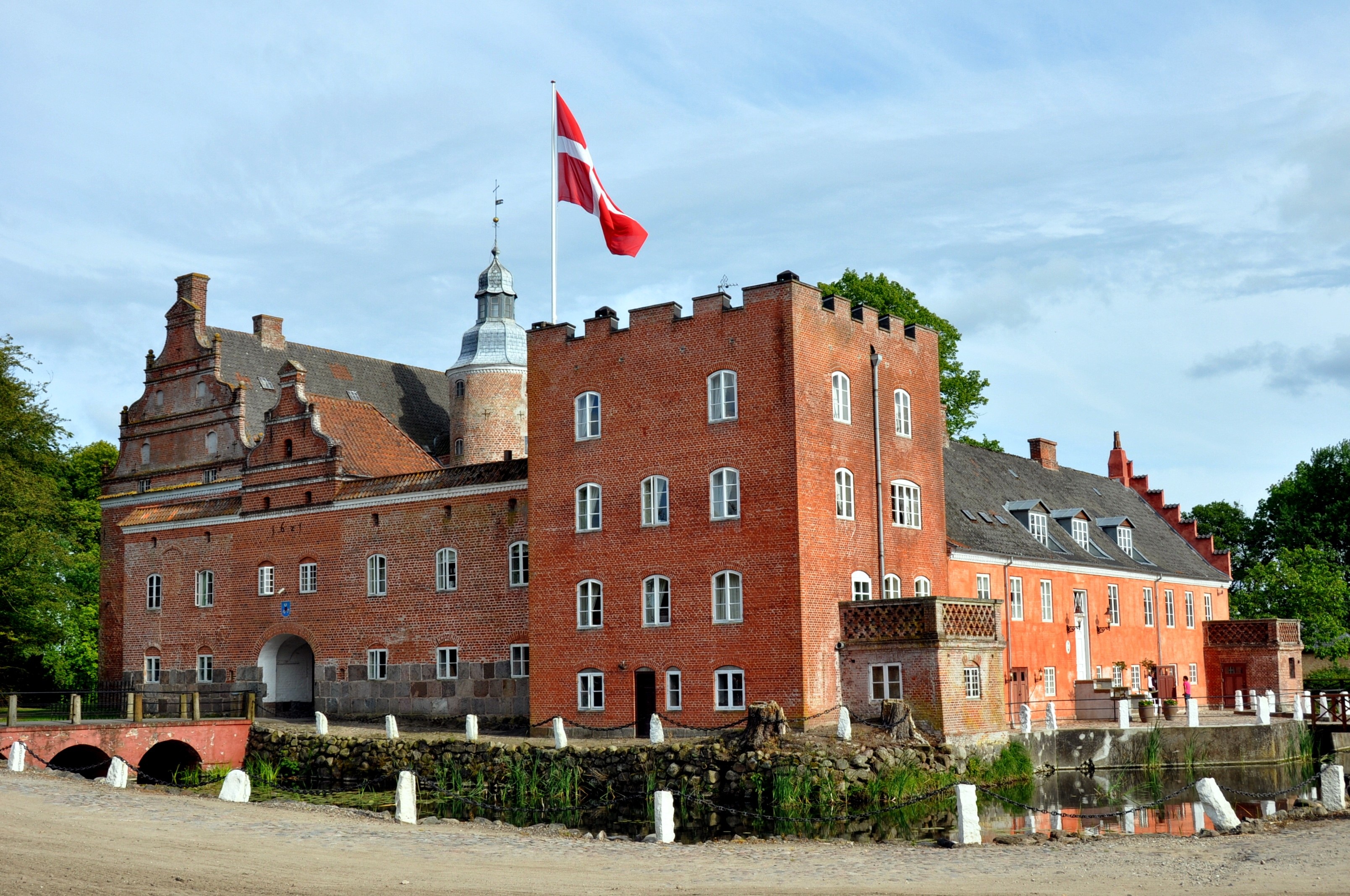Et stort slot i røde mursten, omringet af en voldgrav.