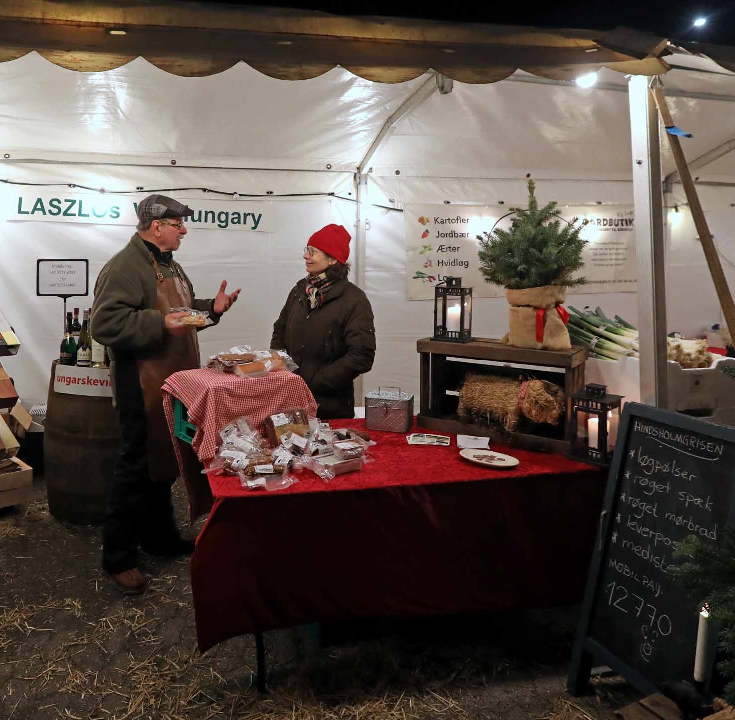 Mand og kvinde i dialog ved madbud til julemarked