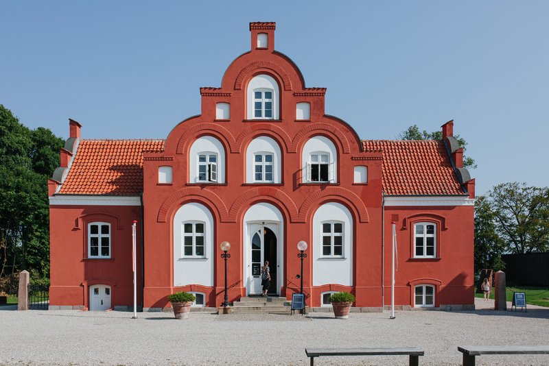 Rød bygning med hvide vinduer og hvidt hegn.