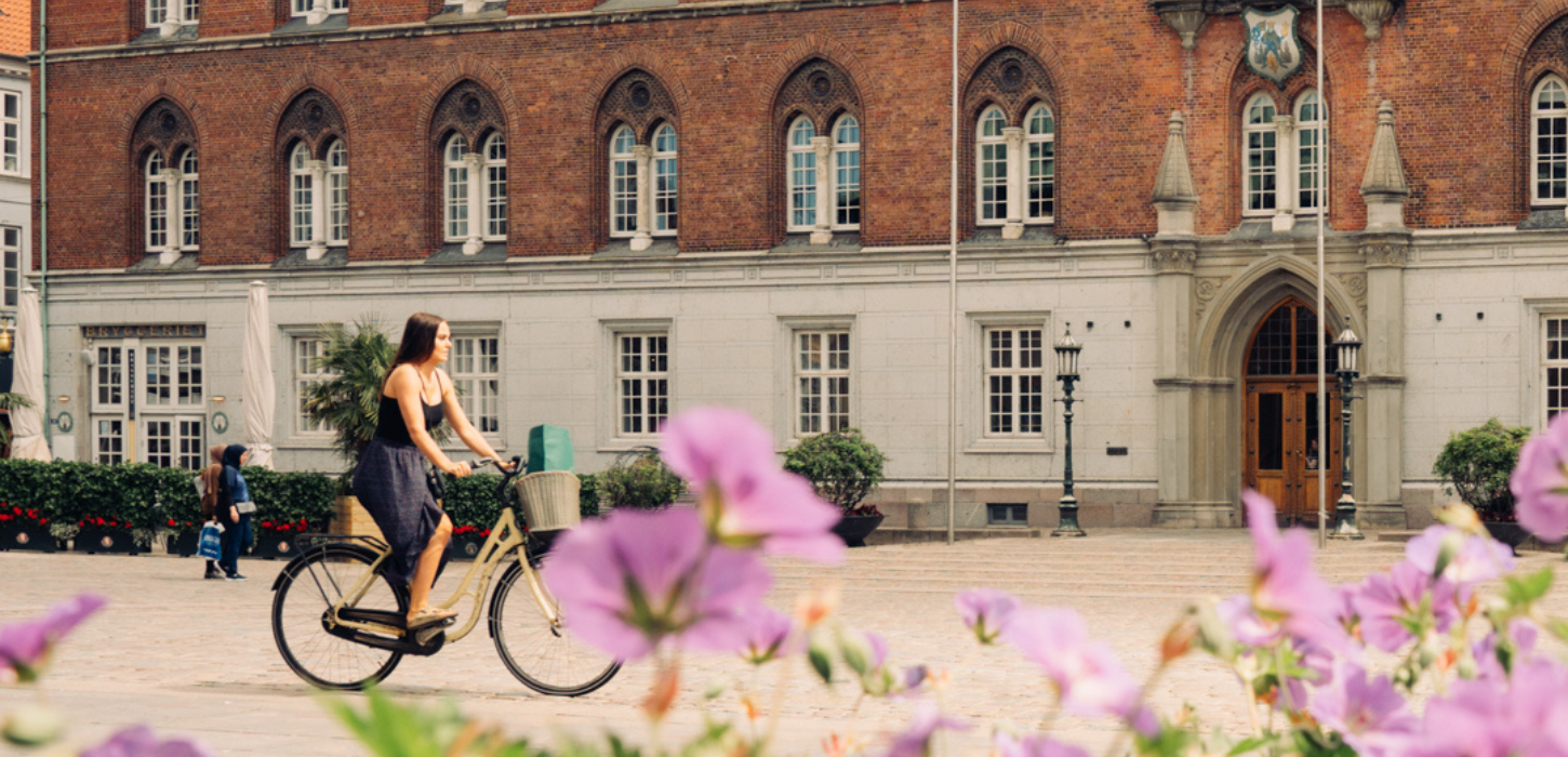 Cyklende kvinde foran bygning
