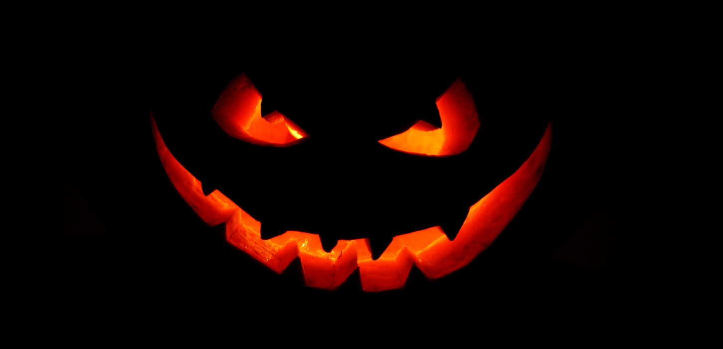 Et udskåret græskar med ansigt på mørk baggrund