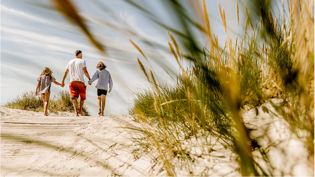 Family walking hand in hand along the beach