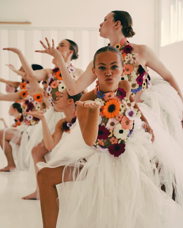 En opvisning af unge kvindelige balletdansere iført hvide klæder og friske blomster