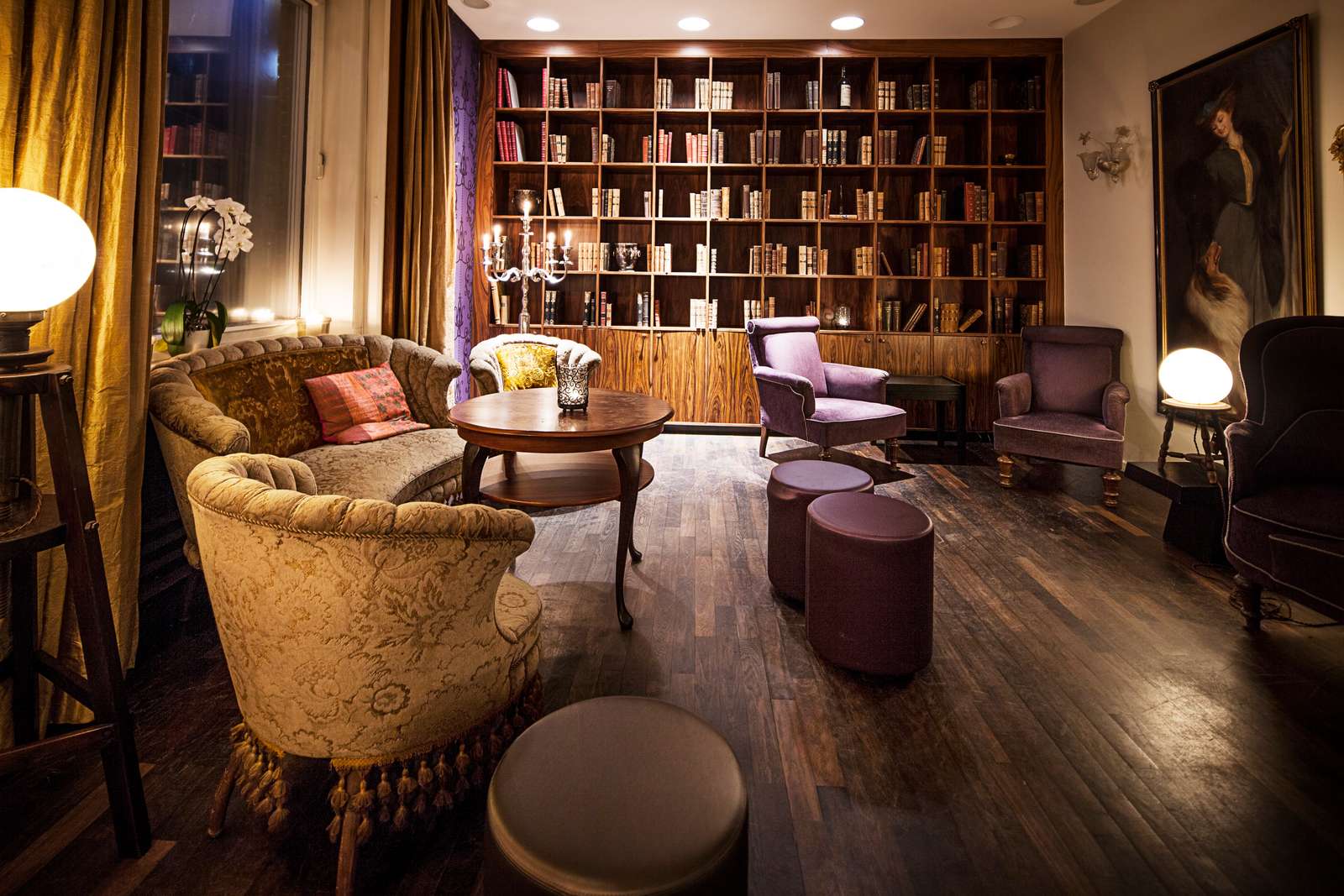 Et oplyst rum med bogreol og bløde stole 