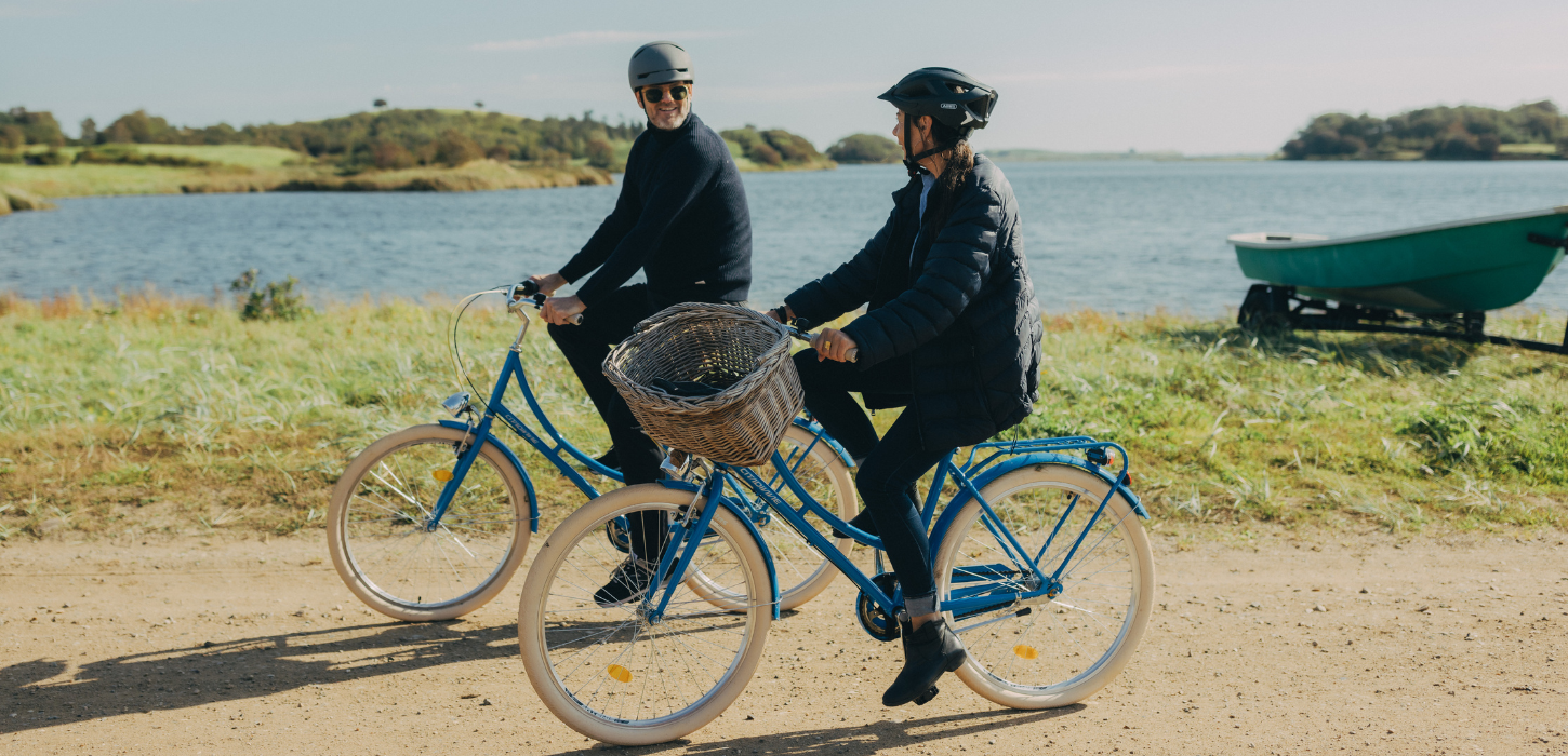 To cyklister på tur på grusvej med hav i baggrunden