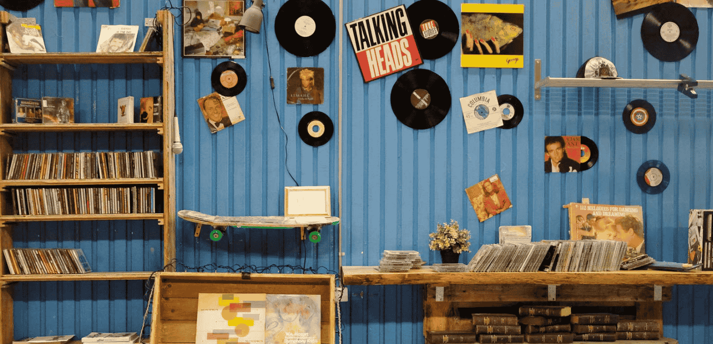 En væg med loppe- og antikfund, fx gamle grammofonplader, bøger, nips og brugskunst.