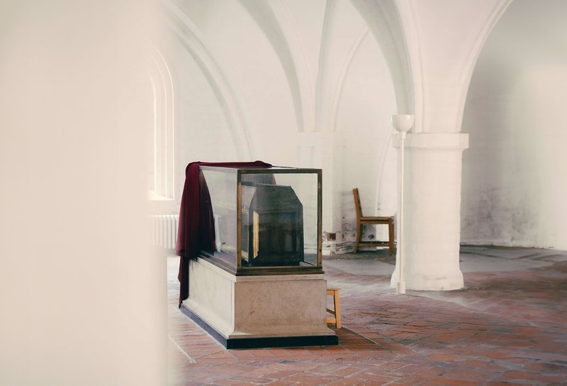 En gravsarkofag i en hvidmalet kirke med hvælvet loft 