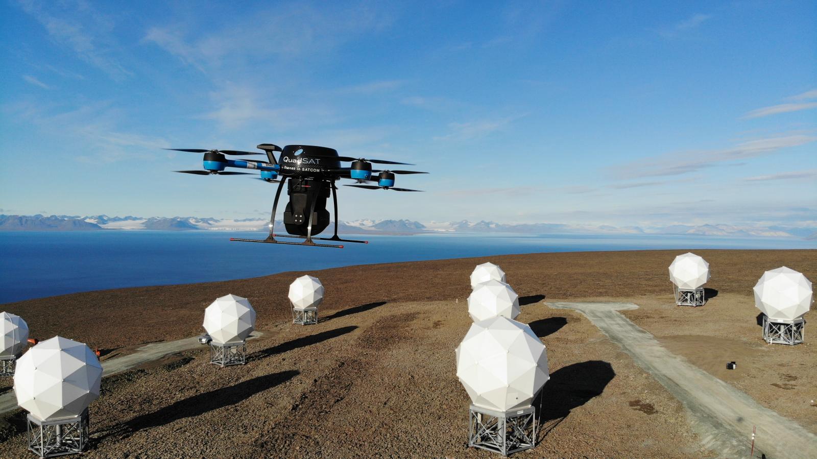 Drone, der flyver hen over nogle hvide elementer op mod en blå himmel