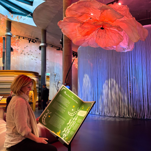 En kvinde sidder og læser i en overdimensioneret bog i en farverig udstilling