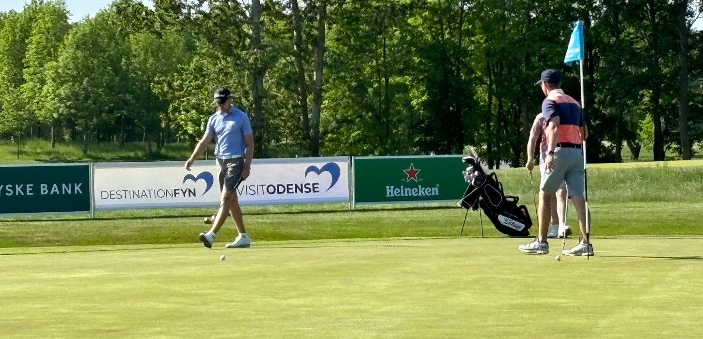 Golfspillere på golfbane med bannere i baggrunden