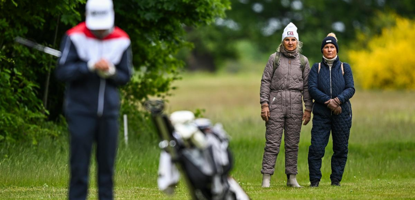 To kvinder står og kigger på en golfspiller