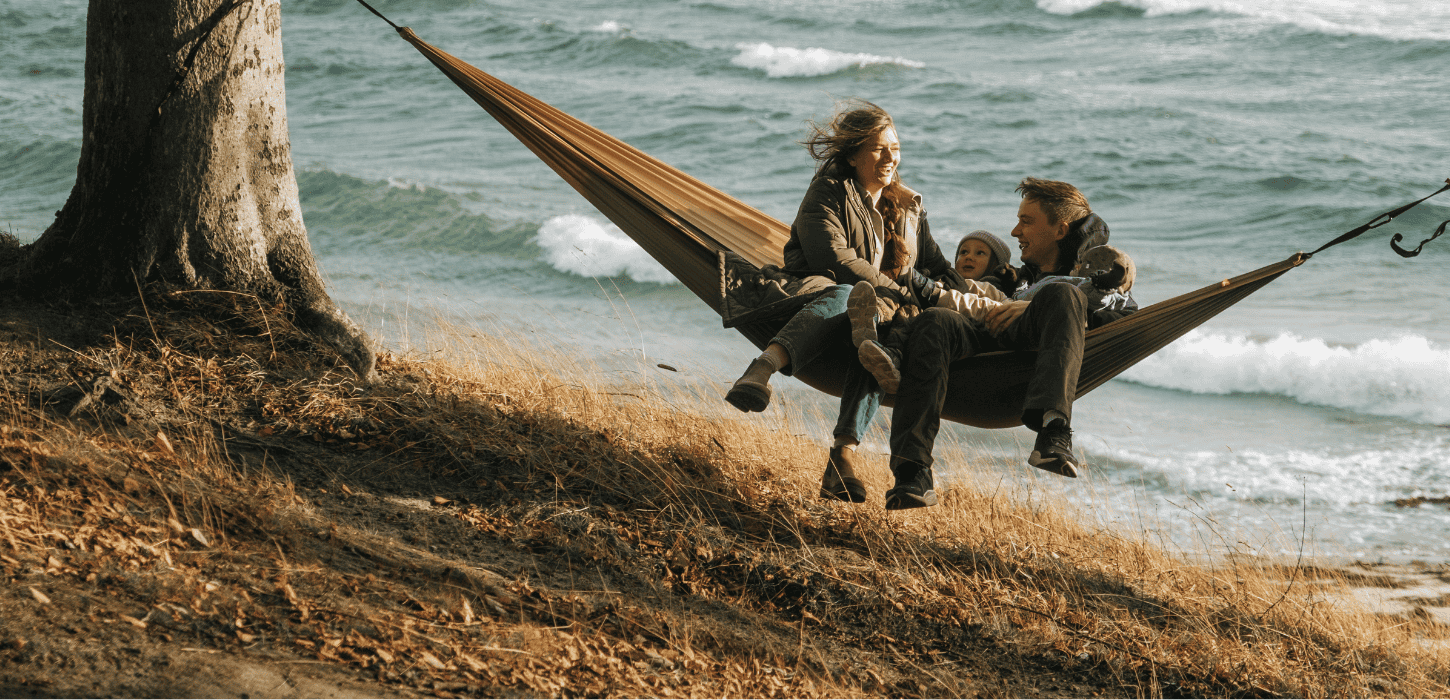 En familie på tre hygger i en hængekøje lige ud til havet på Fyn i Nyborg. 