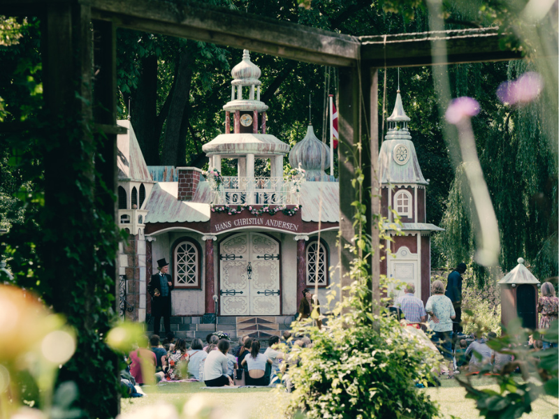En scene formet som et eventyrslot i en grøn park bliver brugt som kulisse til en parade omhandlede eventyrforfatteren fra Odense, H. C. Andersen. 