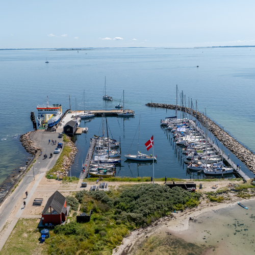 Dronebillede af en mindre hesteskosformet havn på Drejø i Det Sydfynske Øhav en sommerdag