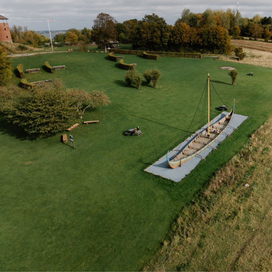 Dronebillede af Munkebo Bakke, som er et højt udkigspunkt, hvor der er en græsplæne med en legeplads formet som et vikingeskib. 