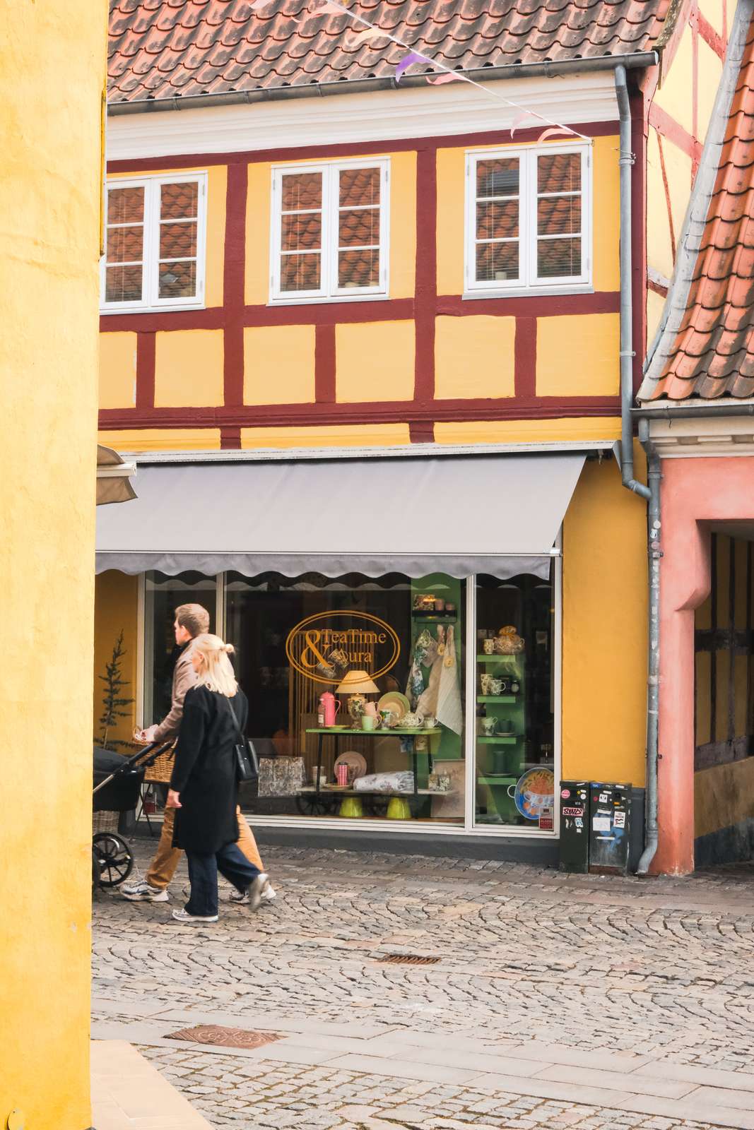 Shoppinggade i Svendborg, hvor et par ruller forbi en butiksfacade med en barnevogn. 
