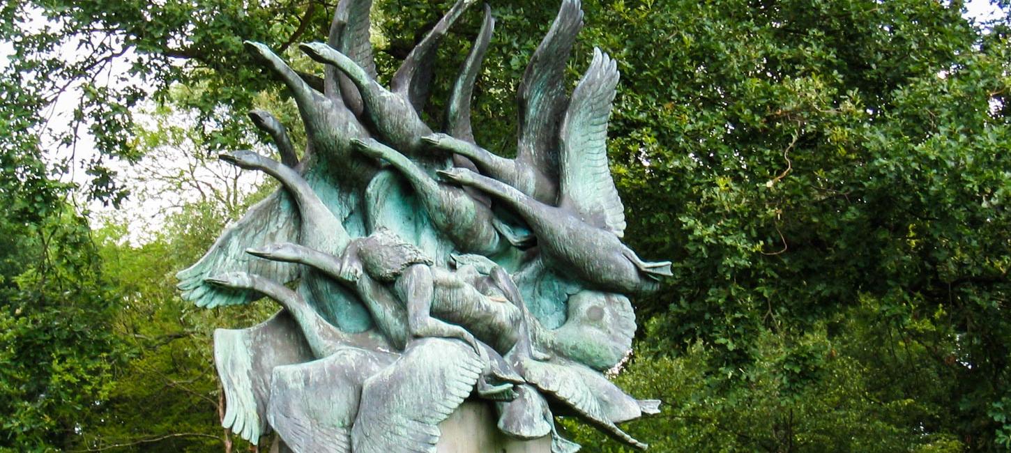 Foran et træ står en skulptur af svaner og en kvinde