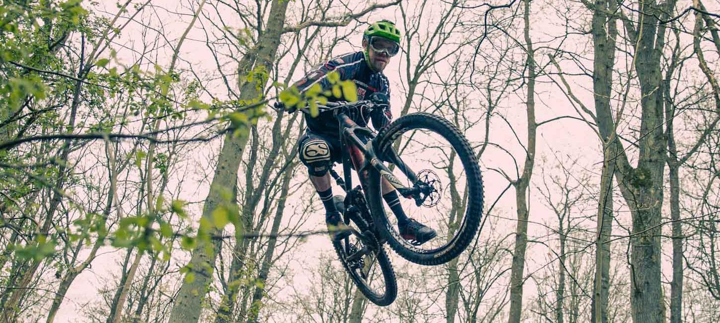 En mountainbiker med grøn hjelm, der er oppe i luften.