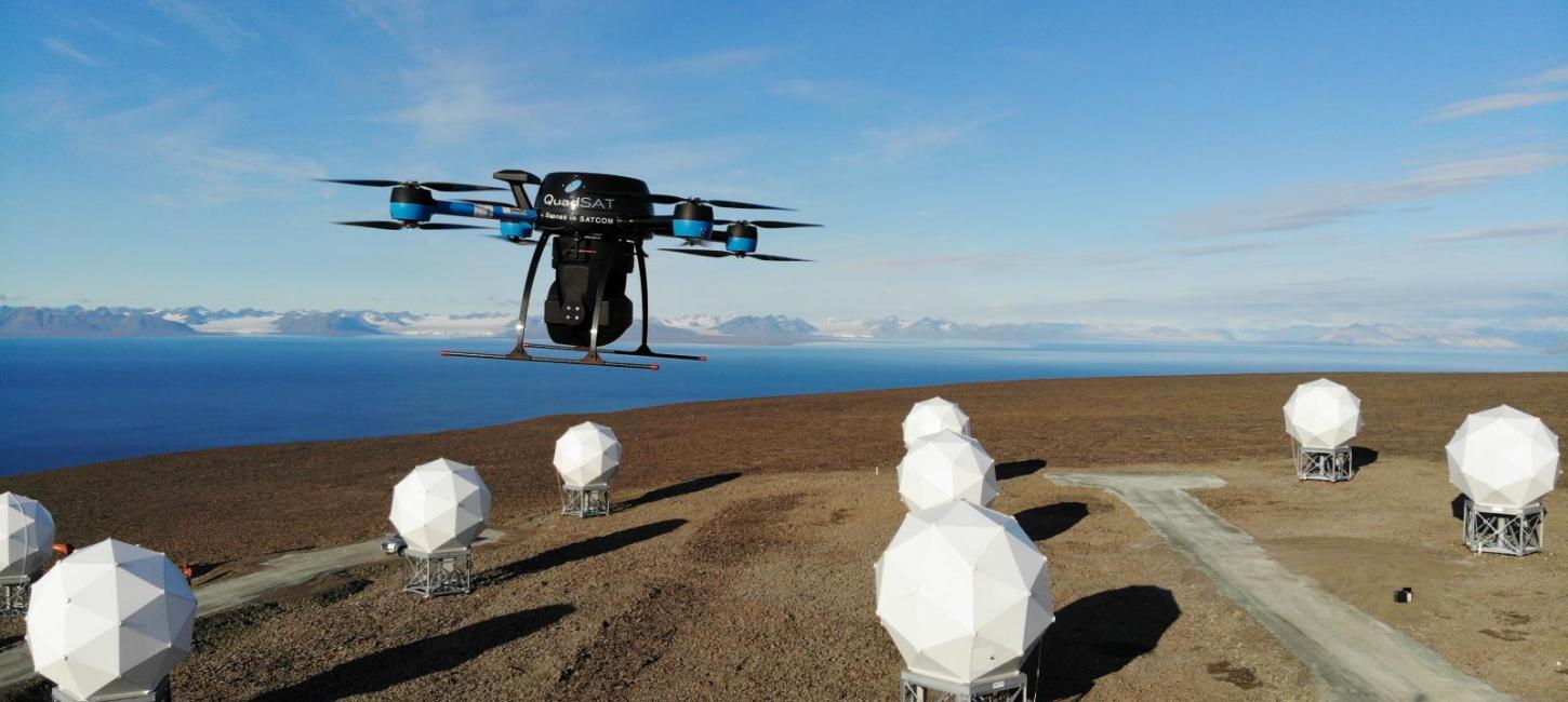 Drone, der flyver hen over nogle hvide elementer op mod en blå himmel