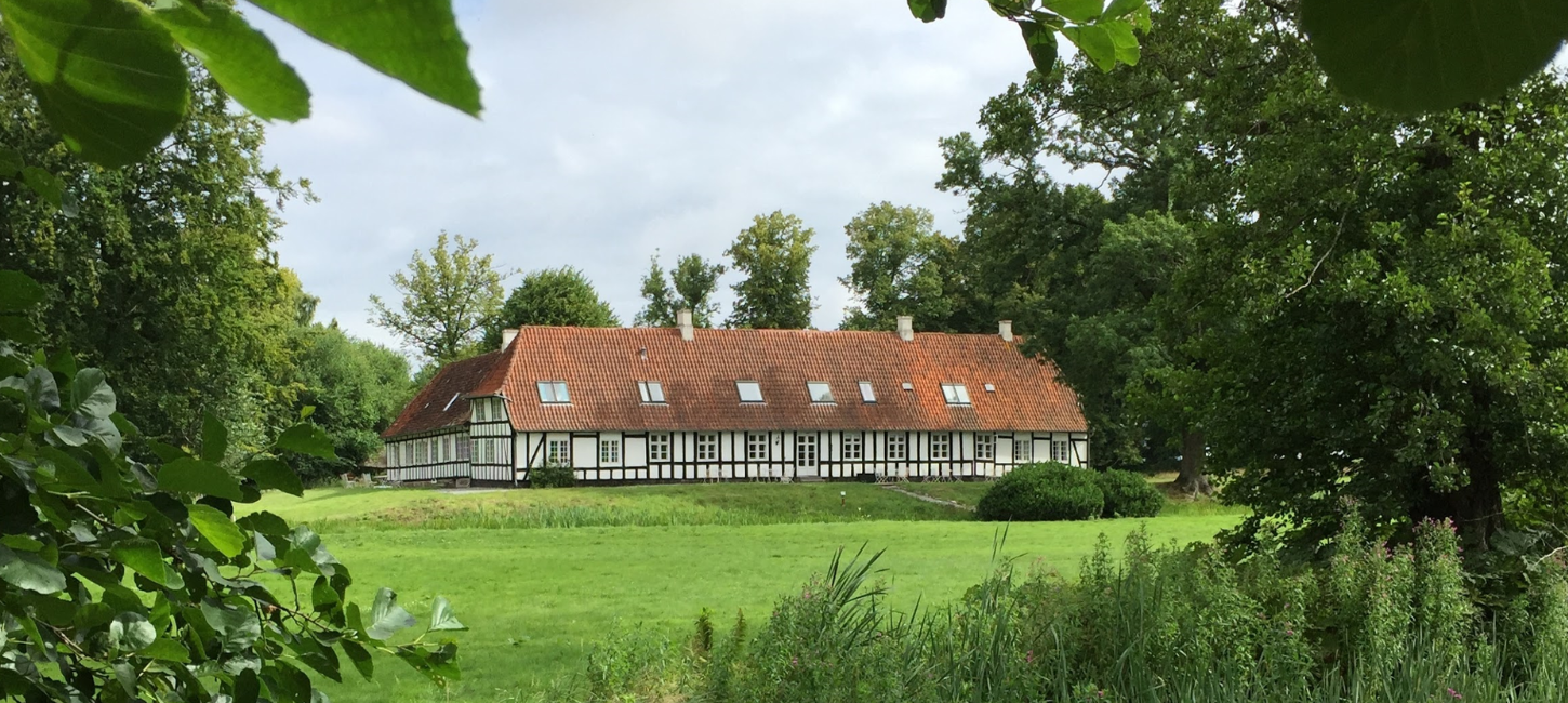 En stor herregård beliggende midt i et frodigt grønt marklandskab.