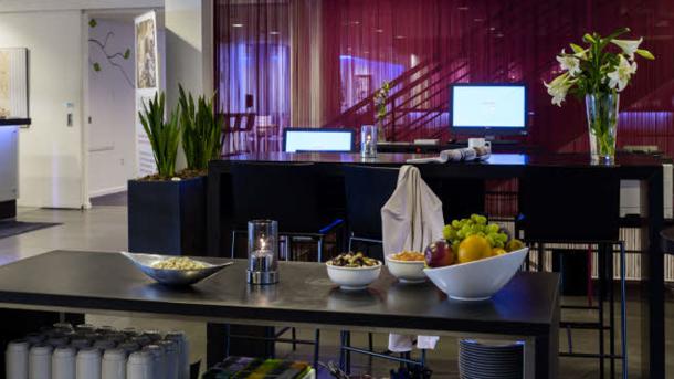 Et hotel set indefra med reception samt borde med frugt og lignende.