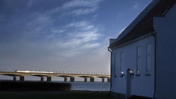 I højre side ses et hvidt hus, og i venstre side mødes havet og himlen i horisonten.  Den er kun brudt af en stor bor, hvorpå der kører et tog.