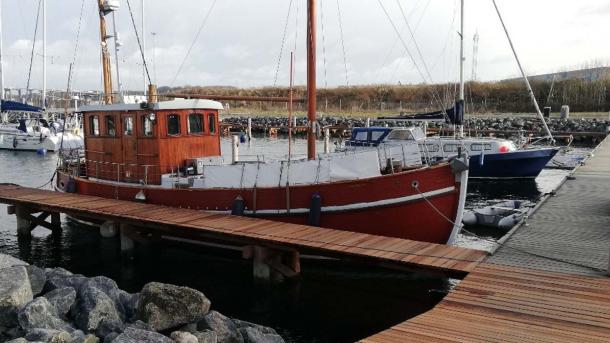 Stor rød sejlbåd ligger til ved havnen. 