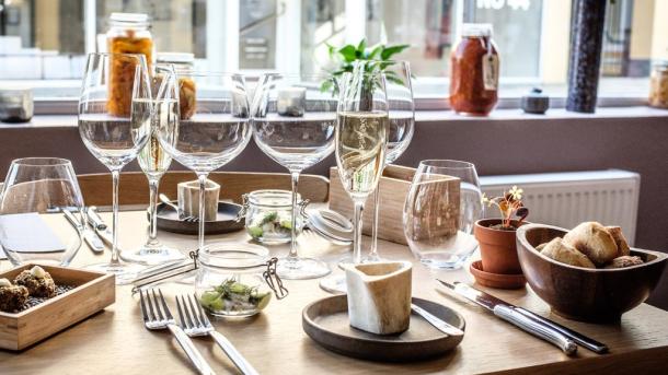 Close-up af et bord på en restaurant, hvor der er serveret vin i glassene og mad på tallerkenerne. 